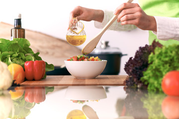 Close Up of human hands cooking vegetable salad in kitchen on the glass table with reflection. Healthy meal, and vegetarian food concept