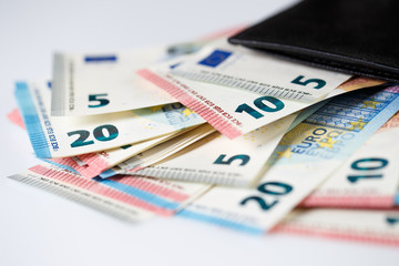 Many euro banknotes in black leather wallet on white background