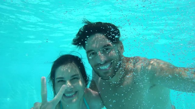 Portrait of couple underwater, resort pool