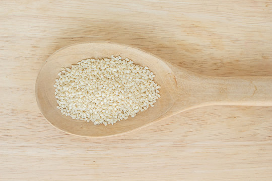 white sesame seeds in spoon on wood backgroud