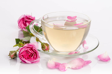 Obraz na płótnie Canvas Glass cup of Tea with roses and petals