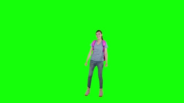 Slow motion of female senior high school jumping while carrying backpack in the studio with green screen background