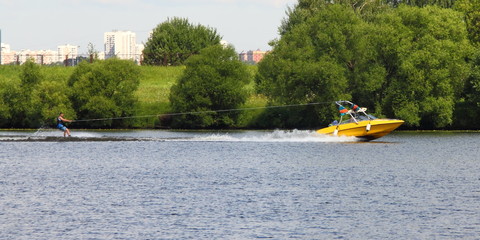 Yellow wakeboard boat with rider in Moscow river on the background of green shore - outdoor activities on the river, water skiing, wakeboard, summer, sports,