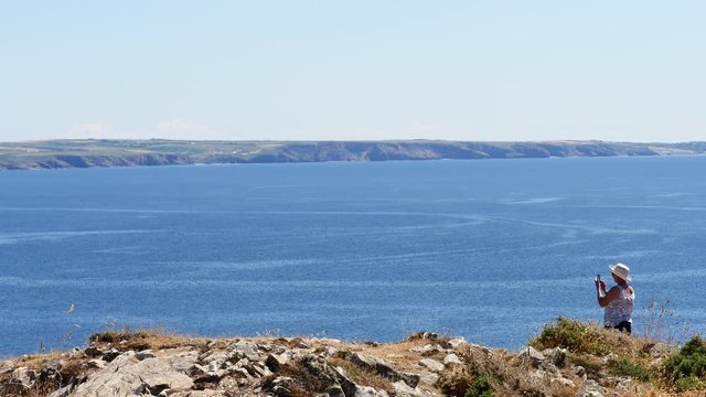 Lady making a panoramic picture with her camera phone Pembrokeshire 