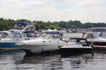 Obraz premium A many powerboats on boat water Parking in the Marina in the summer - storage of ships on the yacht club, side view – luxury lifestyle, recreation, travel