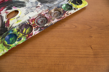 A palette full of old paint on a wood table