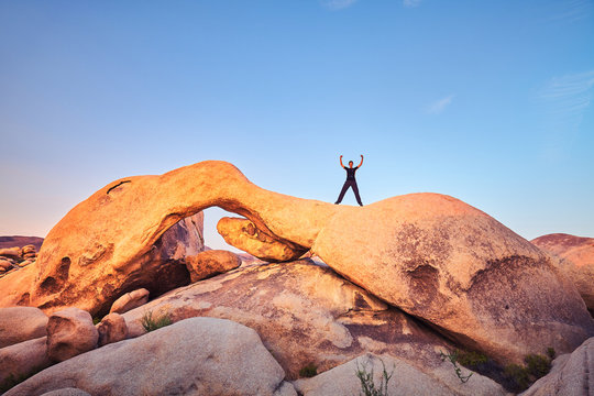 Unique rock formations at Joshua Tree National Park with female climber at sunset, California, USA.