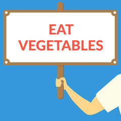 EAT VEGETABLES. Hand holding wooden sign