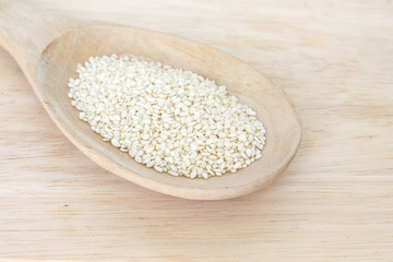 white sesame seeds in spoon on wood backgroud