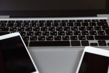 Closeup picture of a keyboard with a phone and tablet lying above it