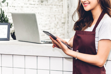Portrait of woman small business owner working behind the counter bar in a cafe.Barista using tablet and receive order from customer