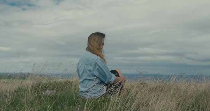 Woman sitting in field turns to look