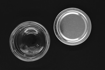 Open glass jar with metal lid on black background surface