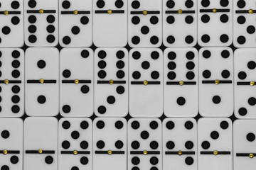 White plastic dominoes with black dots background surface and with gold metal dots in the middle of each dominoes