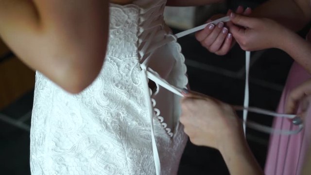 Bridesmaids Helping To Tie Her Wedding Dress. Morning Bride