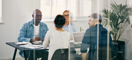 Diverse businesspeople meeting together inside of a glass walled