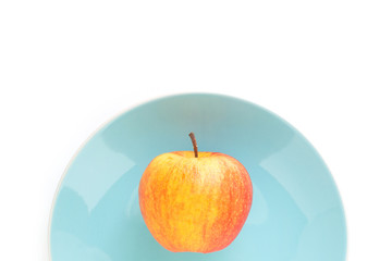 red apple on plate blue top focus on white background
