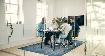 Diverse young businesspeople talking together during a boardroom - obrazy, fototapety, plakaty