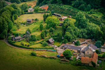 A vantage point view over a small farm in Ardennes, Belgium, with a miniature-like look and feel