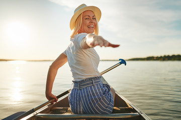 Smiling woman reaching out her hand while paddling a canoe - Powered by Adobe