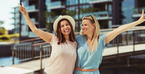 Two young friends laughing while standing together in the city
