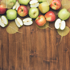 Sweet juicy red and green apples with yellow leaves on wooden background. Free copy space for text. Top view, flat lay