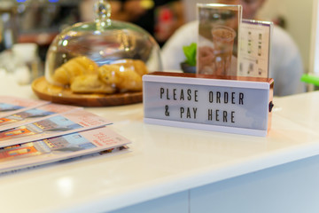 close up of  "please order and pay here" sign on the counter bar of restaurant.