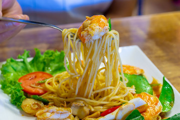 close up of very delicious spicy spaghetti seafood or spaghetti tom yum kung" on white dish