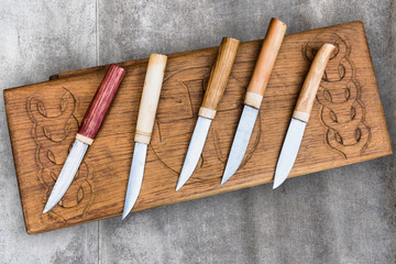 Set of knives with bony handles on a wooden board.
