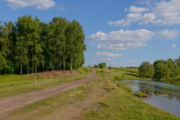 rural dirt road with pillars along the lake and forest