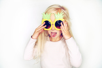 Cute little girl wearing pineapple glasses sticking out her tongue