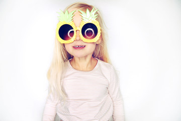 Adorable little girl wearing pineapple glasses making a face