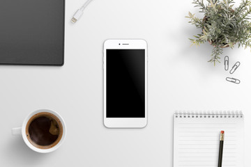 Flat lay scene with white smart phone mockup on office desk. Folder, pen, pad, plant, coffee beside.