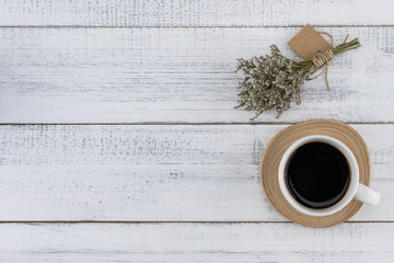 A cup of coffee with caspia bouquet on white wood background with copy space