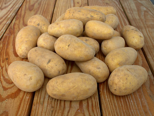 Tubers of fresh potatoes on wooden boards.