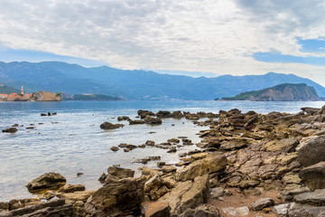Mogren beach with big stones, old city Budva and Sveti Nikola island at Adriatic sea coastline in Montenegro
