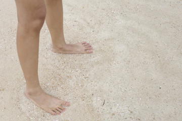 Fototapeta na wymiar Legs of a woman playing sea water at the beach.
