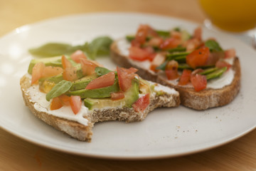 Fototapeta na wymiar Bited homemade healthy toast sandwich with avocado, cheese cream and tomatoe on wooden board. Breakfast healthy food.