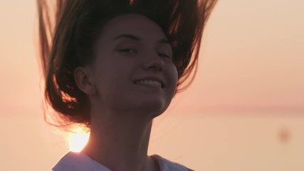 Slow motion teenage girl flipping hair on a beach at sunset
