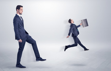 Fototapeta premium Small young man fired by his bos from his workplace with suitcase on his hand 