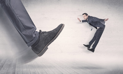 Big foot in a black shoe fire small, young, businessman who is flying away in the space
