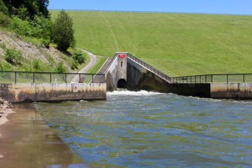 Fototapeta premium The open spillway flowing into the creek water.