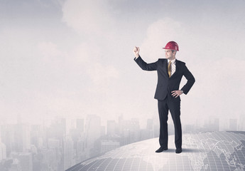 A happy, well dressed construction manager drawing with a pen and planning while standing on top of the earth concept.