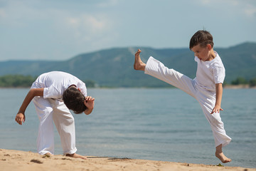 Training of two children on the beach: capoeira, sports