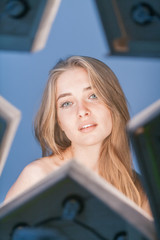 Beautiful young longhaired woman with star reflex in eyes and opened shoulders on blue background