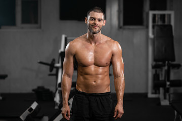 Fototapeta na wymiar Smiling handsome muscular male athlete in gym