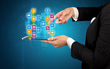 Female elegant hand holding tablet with colourful application icons