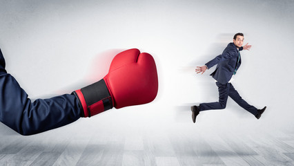 Big red boxing glove knocks out little businessman concept

