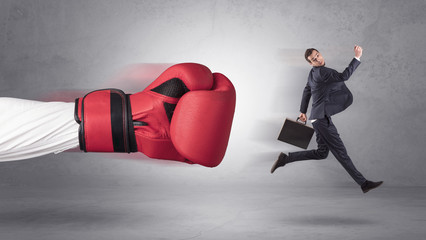 Businessman gets a hit from a giant hand with boxing gloves