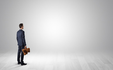 Obraz premium Man standing with his back in an empty room with object in his hand